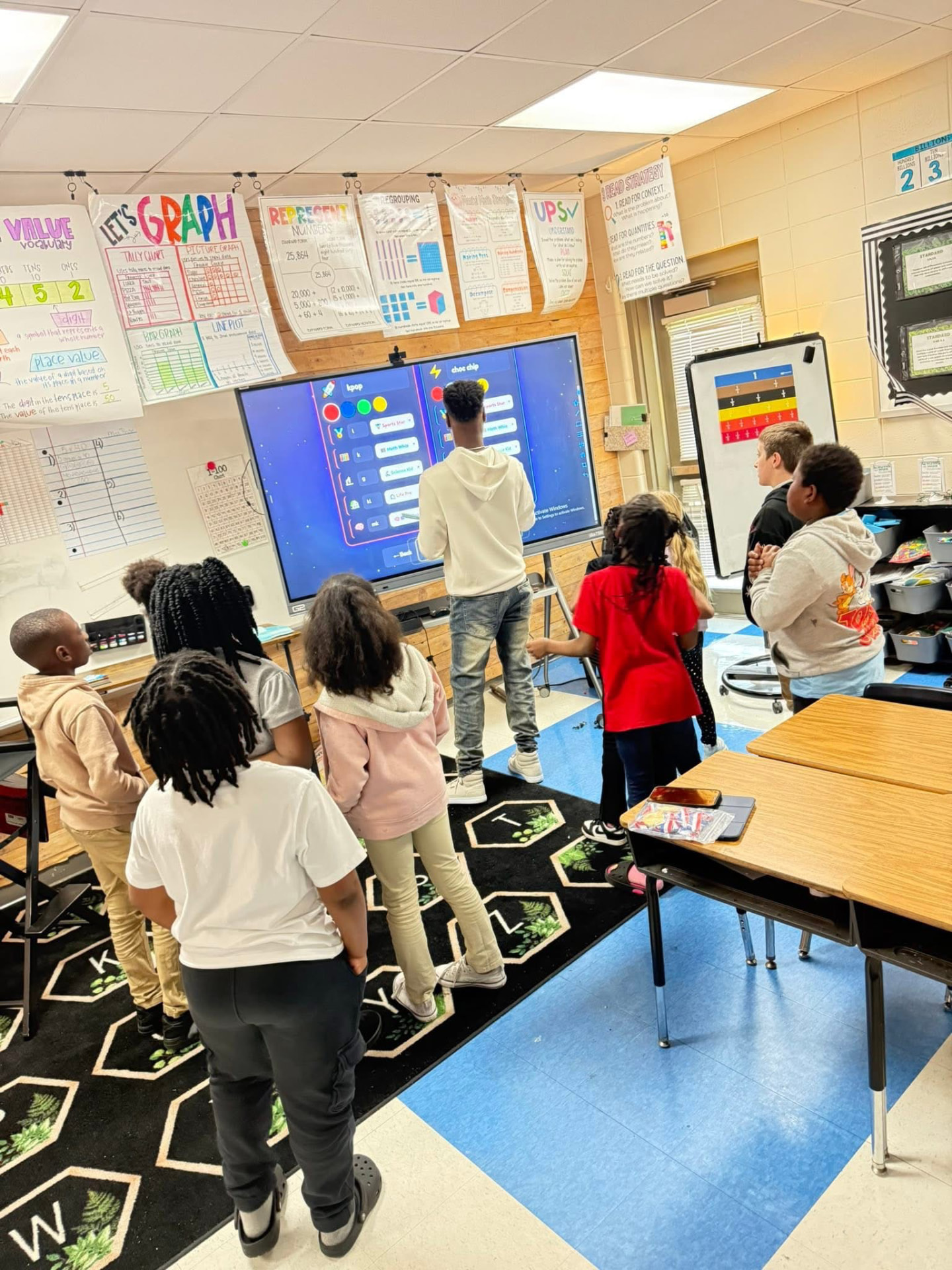 Students gathered around a classroom smartboard during a hands-on AI learning activity