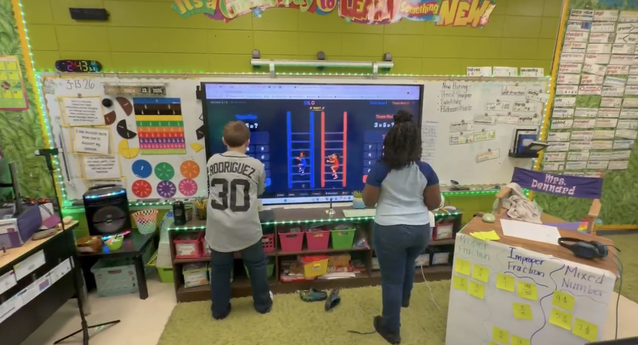 Two learners working at an interactive board during an AI-powered classroom math game
